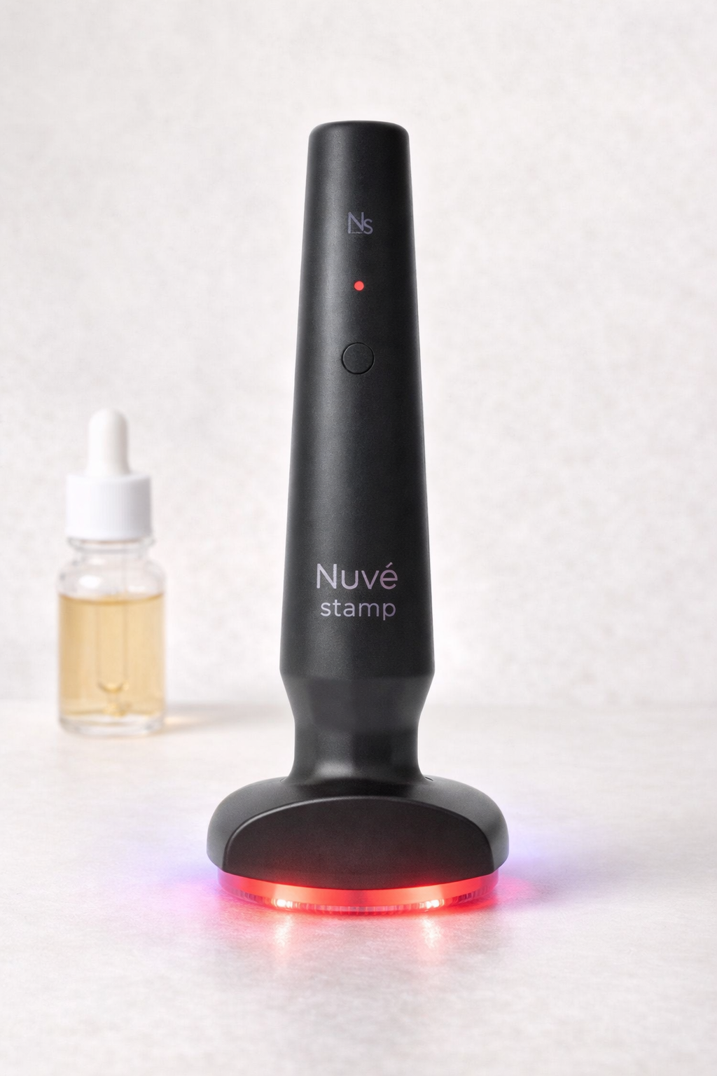 Black Nuve stamp device with a dropper bottle on a white background